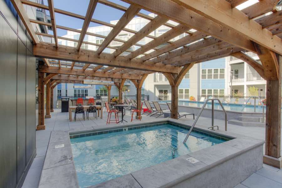 Amenities like this hot tub at Penrose on Mass Apartments help make apartment living worthwhile. Hot tub and wood pergola at apartment building