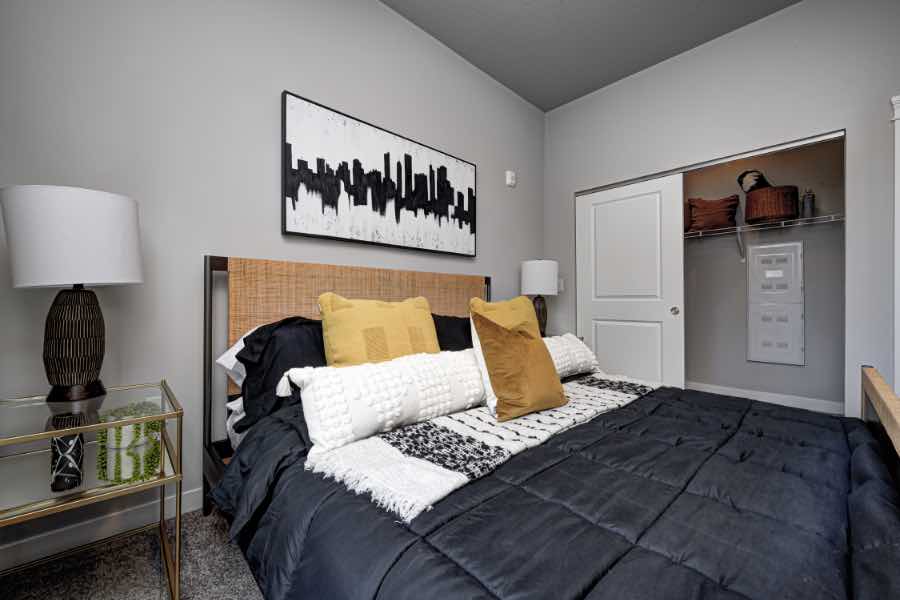 Renters Insurance will help you rest easy at night in bedrooms like this one at Continuum Apartments in West Lafayette. Master bedroom with bed, wall art, and nightstand in apartment