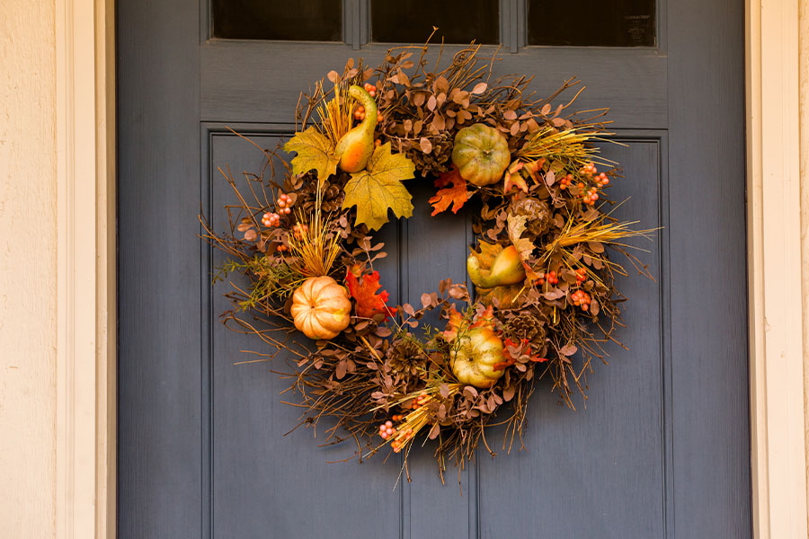 Mark the changing seasons with decorative wreaths on your apartment door. Fall wreath on a navy blue door close up.