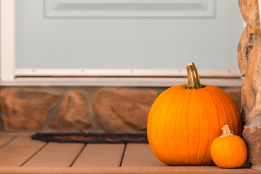 Seasonal decor dresses up your apartment entryway all year long. Two pumpkins on a front porch.