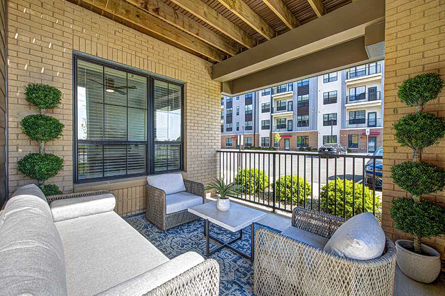 Connecting with a property's Residents will help you decide if you want to move to an apartment like this one at The State at Fishers. Patio with cushioned seating at The State at Fishers Apartments