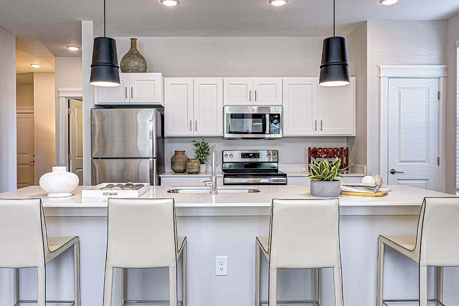 White kitchen with overhead lighting and seating in a new apartment