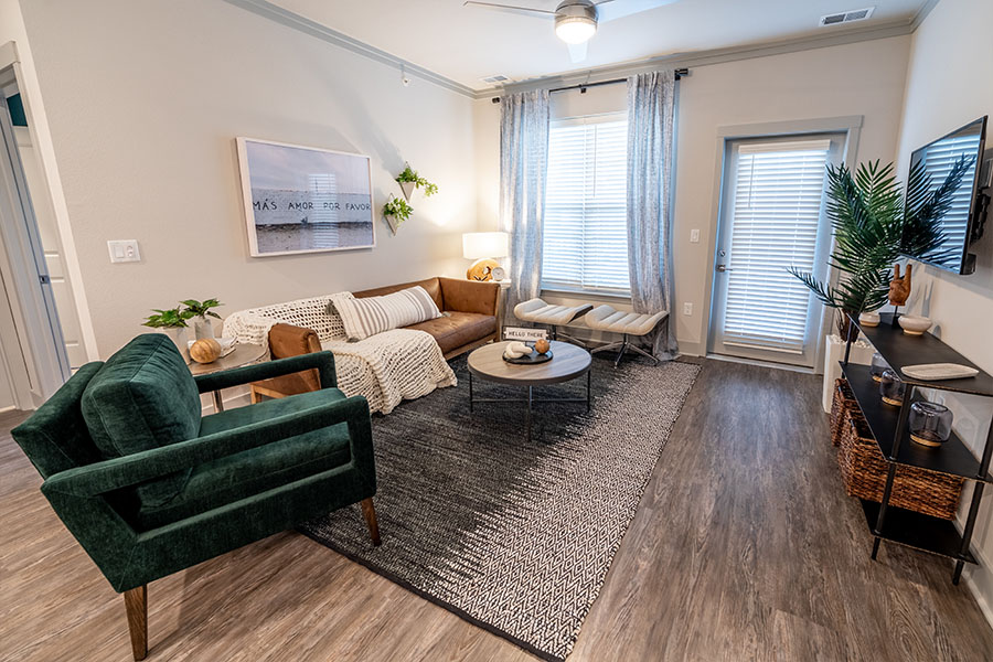 Adding plants to a living room like this one at Verge Luxury Flats can bring a nice, natural feel. Apartment living room with comfy seating and plant life.